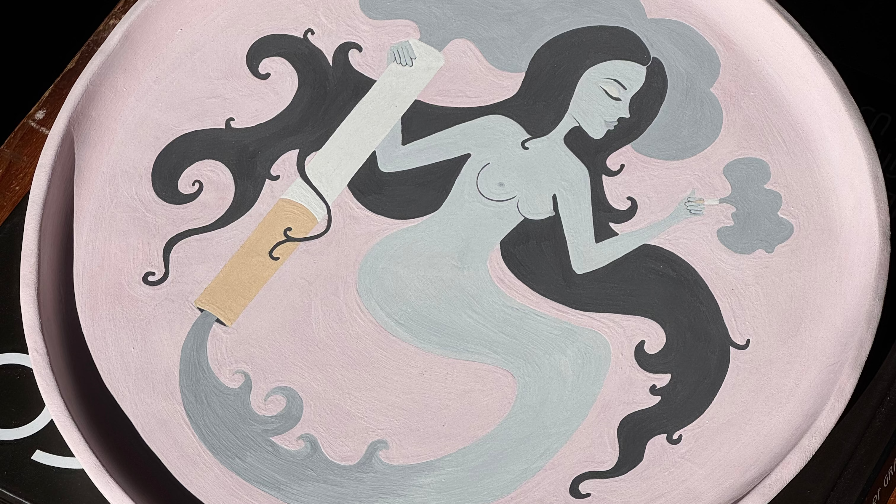 Baby pink ceramic tray with hand painted  sexy smoke lady design on a black art deco coffee table book